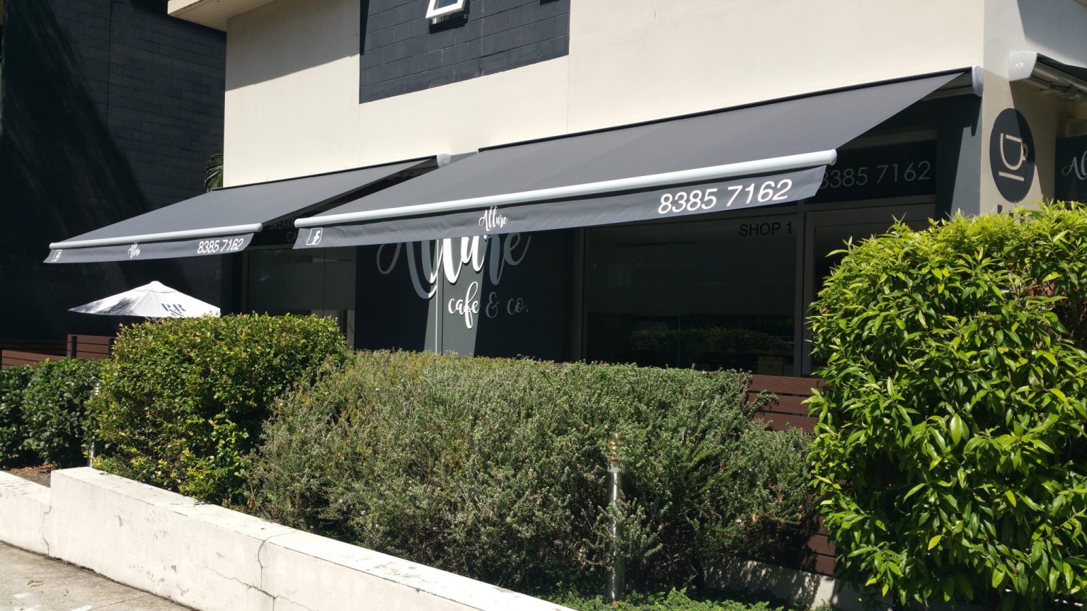 Commercial folding arm awning on a Sydney café — Shutters of Sydney awning repairs