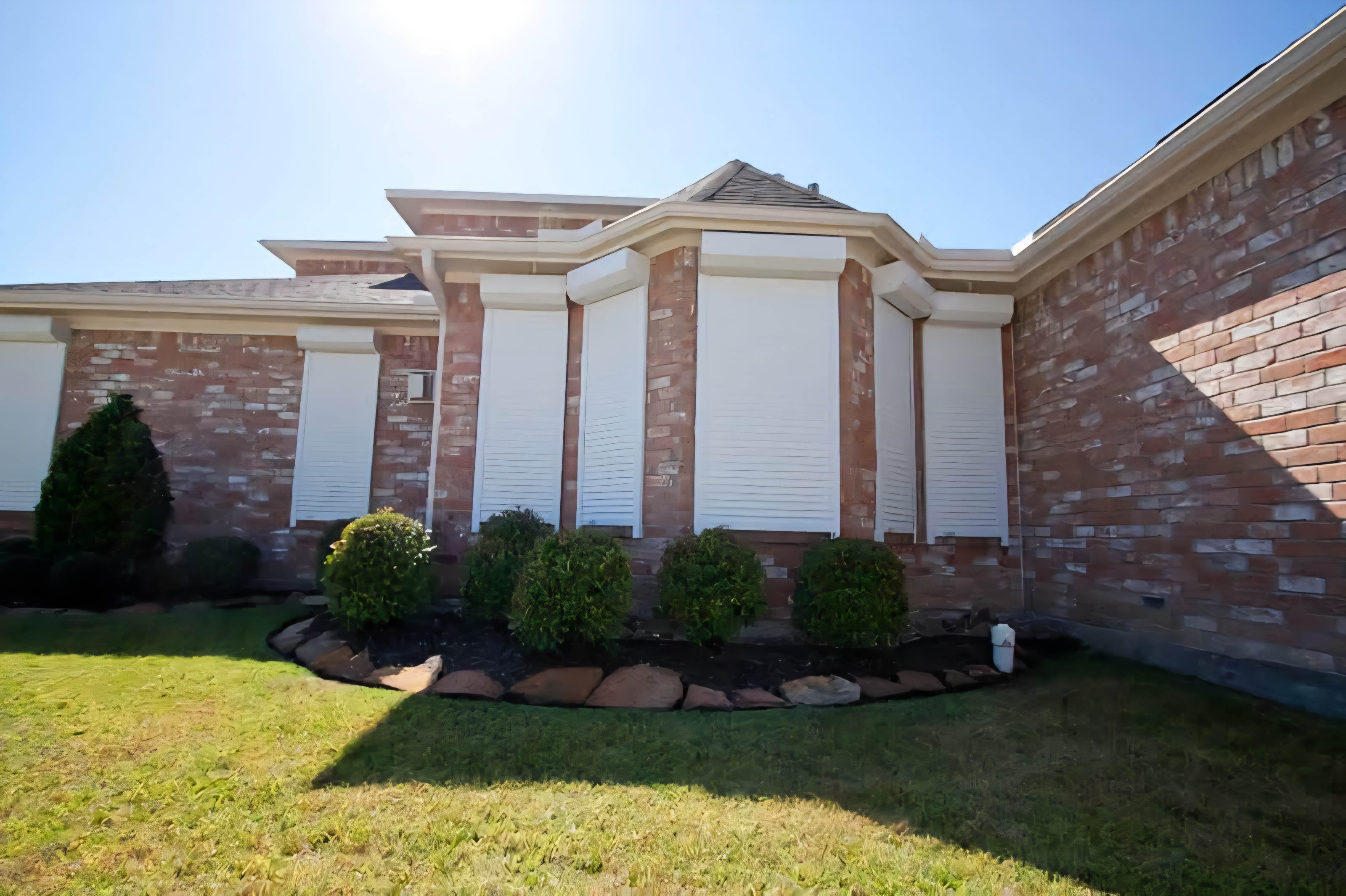 White roller shutters installed across a residential brick facade — Shutters of Sydney Sydney